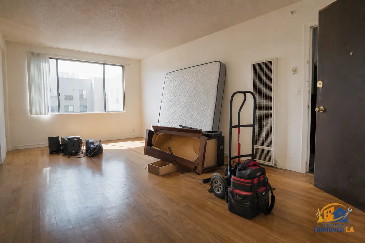 Koreatown studio during junk removal with a mattress, broken dresser, and contractor dolly, showing an LA apartment turnover in progress